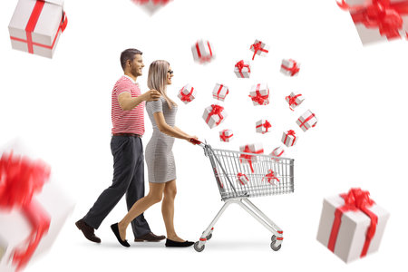 Profile shot of a couple walking and pushing a shopping cart with presents isolated on white backgroundの写真素材