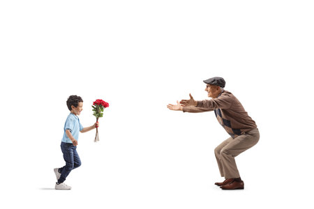 Boy running and giving a bouquet of red roses to his grandfather isolated on white backgroundの写真素材