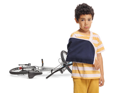 Sad boy with broken arm after bicycle accident isolated on white backgroundの写真素材
