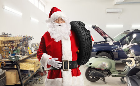 Santa claus in a car garage carrying a car tire on his shoulderの写真素材