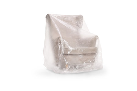 Armchair covered with protective plastic drop cloth isolated on white backgroundの写真素材