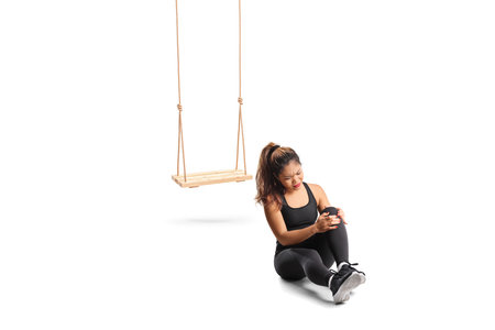 Young woman sitting on the floor and holding her injured knee, swing accident concept isolated on white backgroundの写真素材