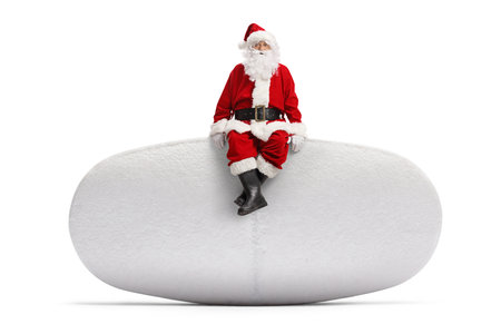 Full length portrait of a Santa Claus sitting on a pill isolated on white backgroundの写真素材