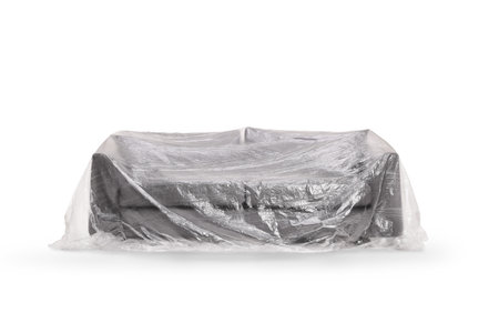 Sofa covered with plastic drop cloth isolated on white backgroundの写真素材