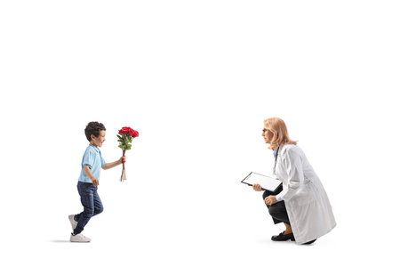 Full length profile shot of a boy bringing flowers to a female doctor isolated on white backgroundの写真素材