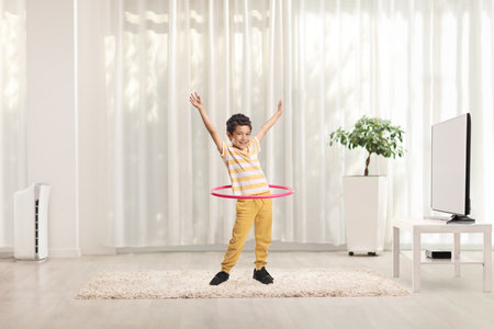 Asian boy spinning a hula hoop at homeの写真素材