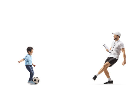 Football coach kicking a ball with a kid isolated on white backgroundの写真素材