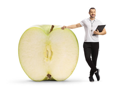 Sports coach holding a clipboard and standing next to a big apple isolated on white backgroundの写真素材