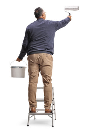 Rear view shot of a mature man on a ladder painting a wall isolated on white backgroundの写真素材