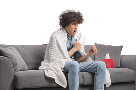 Young man feeling unwell and checking body temperature isolated on white backgroundの写真素材