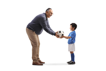 Mature man giving a football to a boy isolated on white backgroundの写真素材