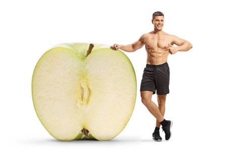 Bodybuilder with a big apple cut in half isolated on white backgroundの写真素材