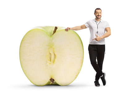 Sports coach pointing at an apple cut in half isolated on white backgroundの写真素材