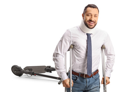 Scooter accident and injured man with a cervical collar leaning on crutches isolated on white backgroundの写真素材