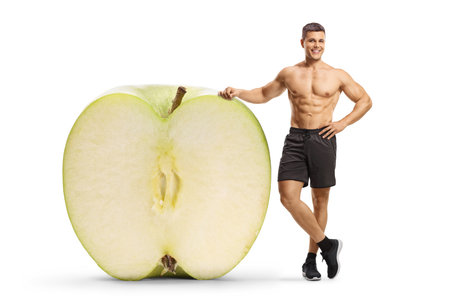 Bodybuilder with a green apple isolated on white backgroundの写真素材