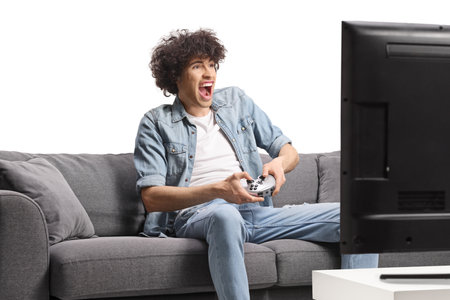 Excited young man sitting on a sofa and playing video games isolated on white backgroundの写真素材