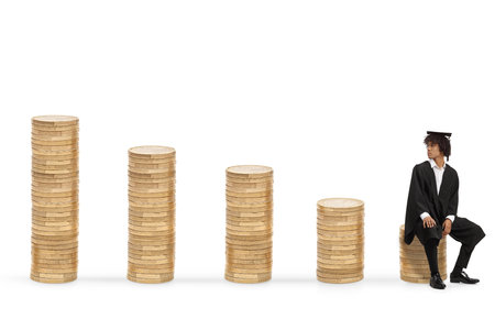 Male african american graduate student sitting on a pile of coins and looking back isolated on white backgroundの写真素材