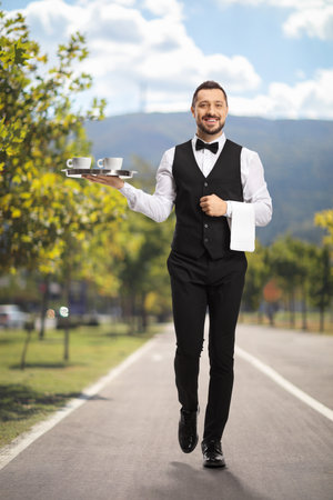 Waiter carrying coffee on a tray outdoorsの写真素材