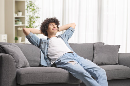 Relaxed young man enjoying on a sofa at homeの写真素材