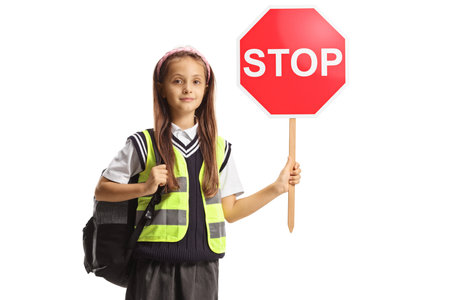 Schoolgirl with a stop sign and safety vest isolated on white backgroundの写真素材