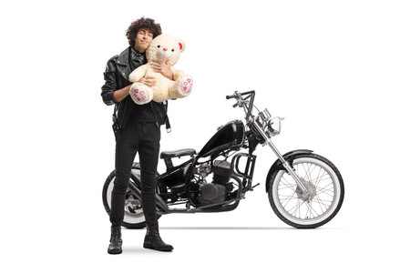 Biker in a leather jacket standing and hugging a teddy bear isolated on white backgroundの写真素材