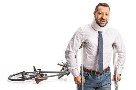 Bicycle accident and an injured man with a cervical collar leaning on crutches isolated on white backgroundの写真素材