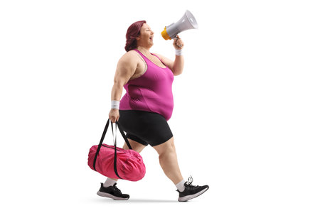 Full length profile shot of a plus size woman with a sports bag holding a megaphone and walking isolated on white backgroundの写真素材