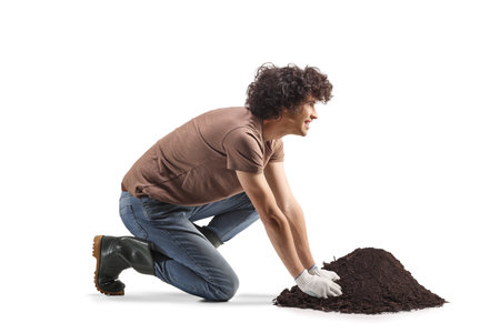 Man kneeling with a pile of earth isolated on white backgroundの写真素材