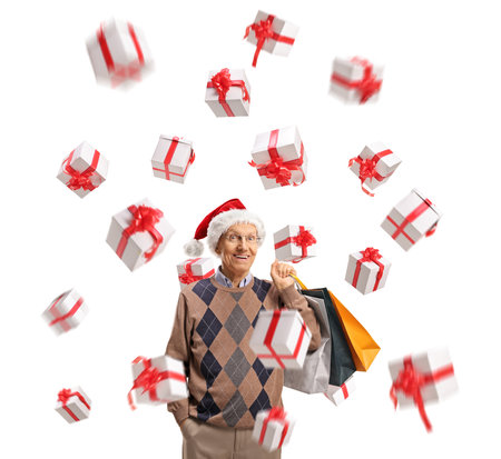 Elderly gentleman with a santa claus hat and presents holding shopping bags isolated on white backgroundの写真素材