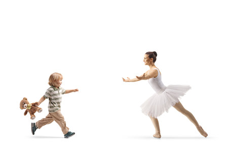 Child with a teddy bear running to hug a ballerina isolated on white backgroundの写真素材