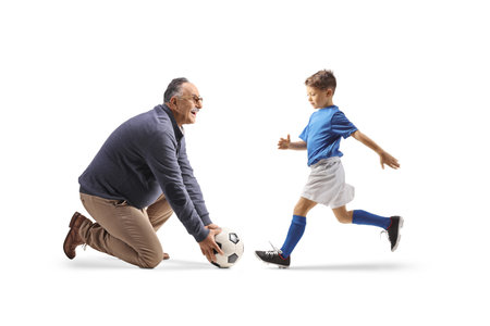 Boy running and mature man kneeling and holding a football isolated on white backgroundの写真素材