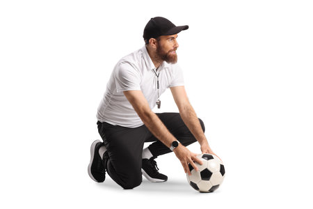 Sports coach holding a football and kneeling isolated on white backgroundの写真素材