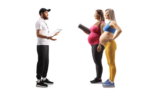 Full length shot of a fitness coach talking to pregnant women isolated on white backgroundの写真素材
