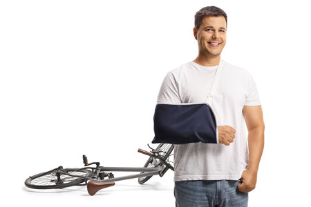 Young man with a broken arm injured in a bicycle accident isolated on white backgroundの写真素材