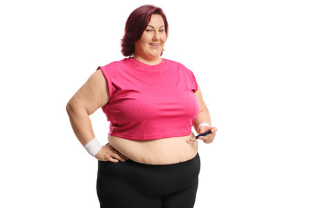 Overweight woman poking abdomen with an insulin pen isolated on white backgroundの写真素材