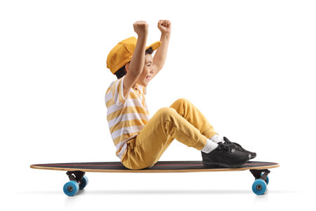 Happy boy sitting and riding on a longboard isolated on white backgroundの写真素材