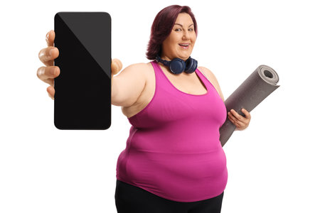 Plus size woman in sportswear showing a smartphone isolated on white backgroundの写真素材