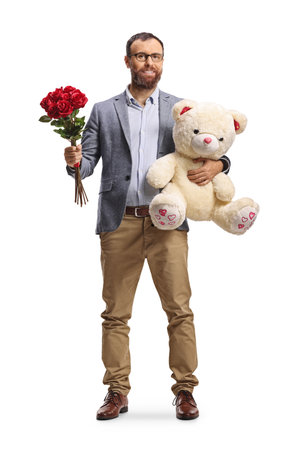 Full length portrait of a man holding a teddy bear and red roses isolated on white backgroundの写真素材