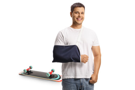 Young man with a broken arm recovering from skateboard accident isolated on white backgroundの写真素材