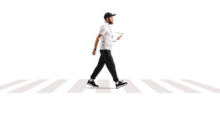 Full length profile shot of a PE teacher walking at zebra crossing isolated on white backgroundの写真素材