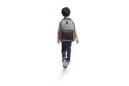 Rear view shot of a boy with a backpack walking isolated on white backgroundの写真素材