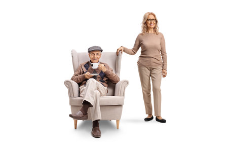 Woman standing next to a an elderly man in an armchair isolated on white backgroundの写真素材