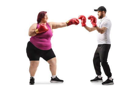 Corpulent woman training box with a coach, weight loss concept isolated on white backgroundの写真素材