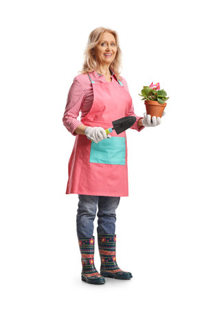 Woman gardener holding a flower pot and a spade isolated on white backgroundの写真素材