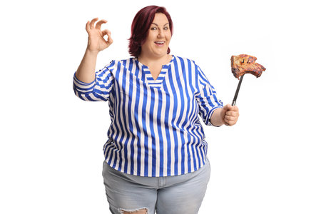 Woman holding grilled meat on a fork and gesturing ok sign isolated on white backgroundの写真素材
