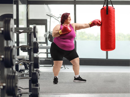 Woman training box at a gym with a punch bag, weight loss conceptの写真素材