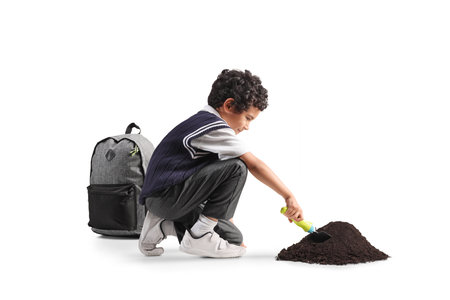 Schoolboy digging a pile of earth isolated on white backgroundの写真素材