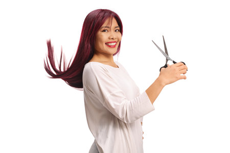 Asian woman with long hair holding scissors isolated on white backgroundの写真素材