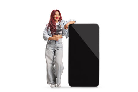 Asian woman leaning on a big mobile phone and pointing isolated on white backgroundの写真素材
