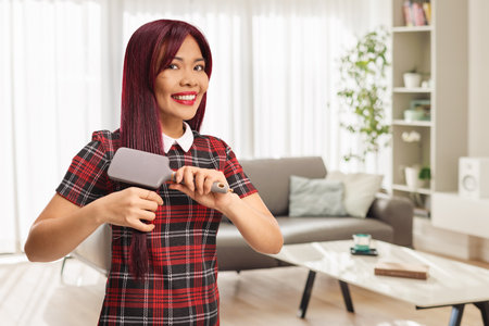 Young asian woman brushing her hair at homeの写真素材